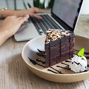 Cake shop owner working on a laptop, with a cake next to her