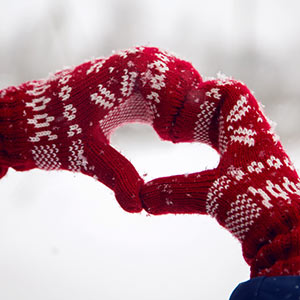 Knitted gloves making a heart sign in a snowy scene