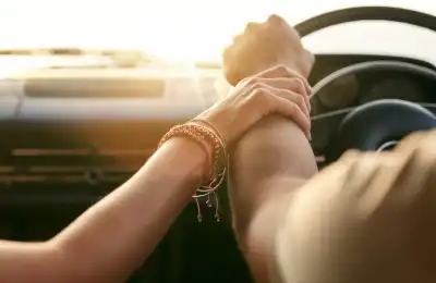 Image of someone holding someone's arm whilst driving.