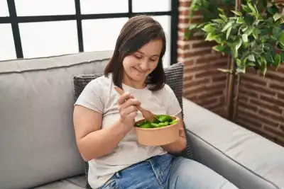 dark haired woman eating a tub of salad