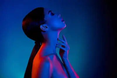 A woman with her head tilted back and eyes closed with a dark background