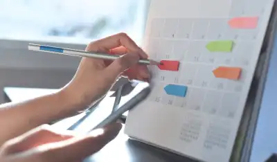 person writing dates in calendar