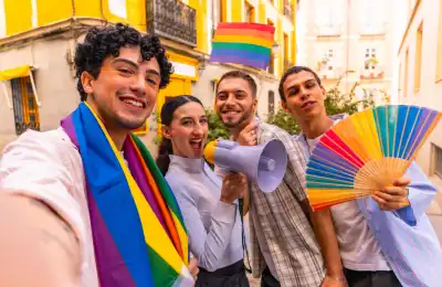 people at the Pride parade wearing rainbow flags
