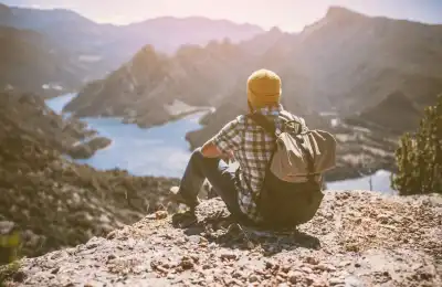 Image of someone sitting on top of a mountain being independent.