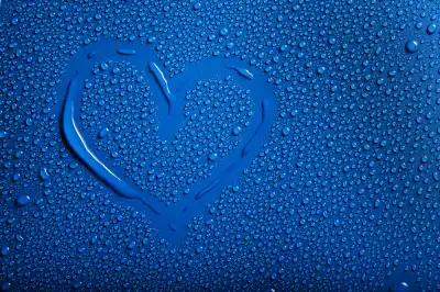 Blue background with lots of drops of condensation and water with a heart drawn on