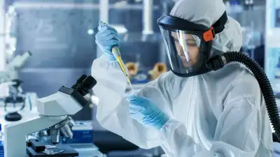 Someone in a protective suit and mask, experimenting with various liquids