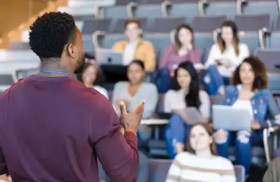 Image of a teacher and students in a lecture theatre.