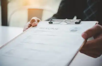 person handing over a printed resume on clipboard