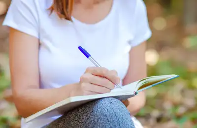 woman writing in notebook outside