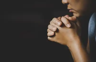 close up of woman praying in dark room