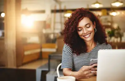 Image of a woman smiling at her phone.