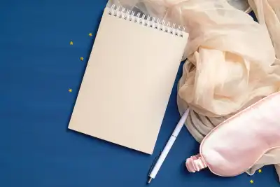 An eye mask next to a notepad and pen
