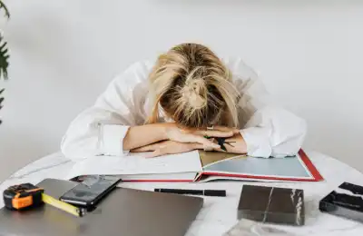 burned-out woman with head in hands at desk
