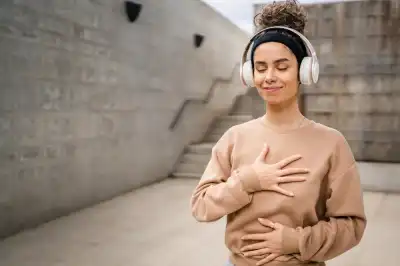 A woman outside with her eyes closed, smiling, with a hand on her chest and the other hand on her stomach