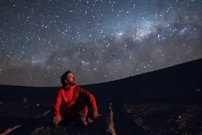A man sat beneath the stars looking at constellations