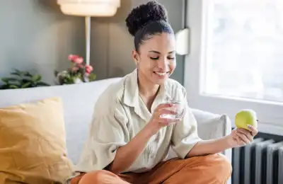 Image of someone eating an apple and drinking water.