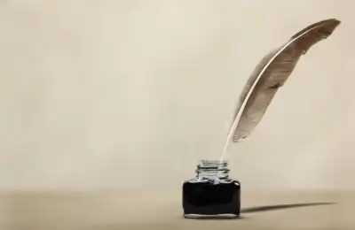 feather quill dipped into ink pot