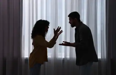 Couple arguing silhouetted against window