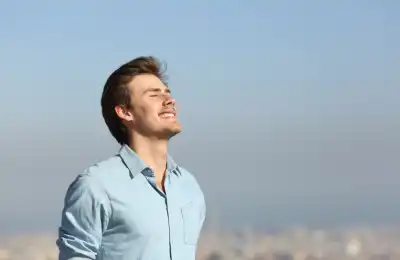 Image of a man outdoors smiling with his eyes closed.