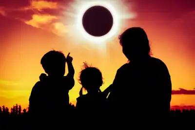 Silhouettes of three people watching a solar eclipse