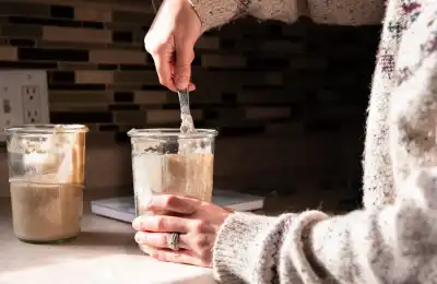 person holding a glass jar of sourdough starter