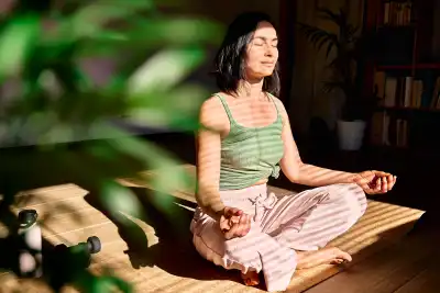 A woman sat cross legged, eyes closed, meditating