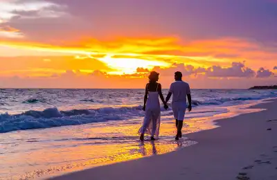 couple walking on beach at sunset