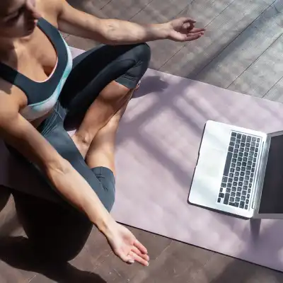 Top view of a woman learning to be a yoga teacher by following lessons on a laptop.