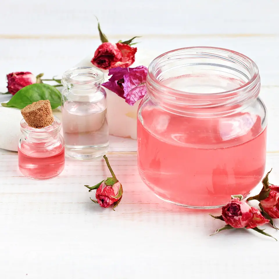 Jars of rose water alongside dried flowers