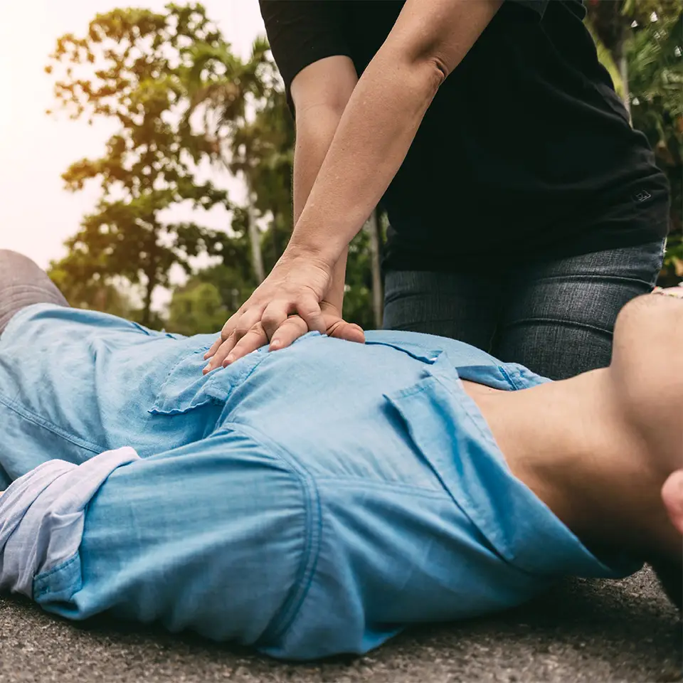 A person performing CPR on someone who is lying on the ground