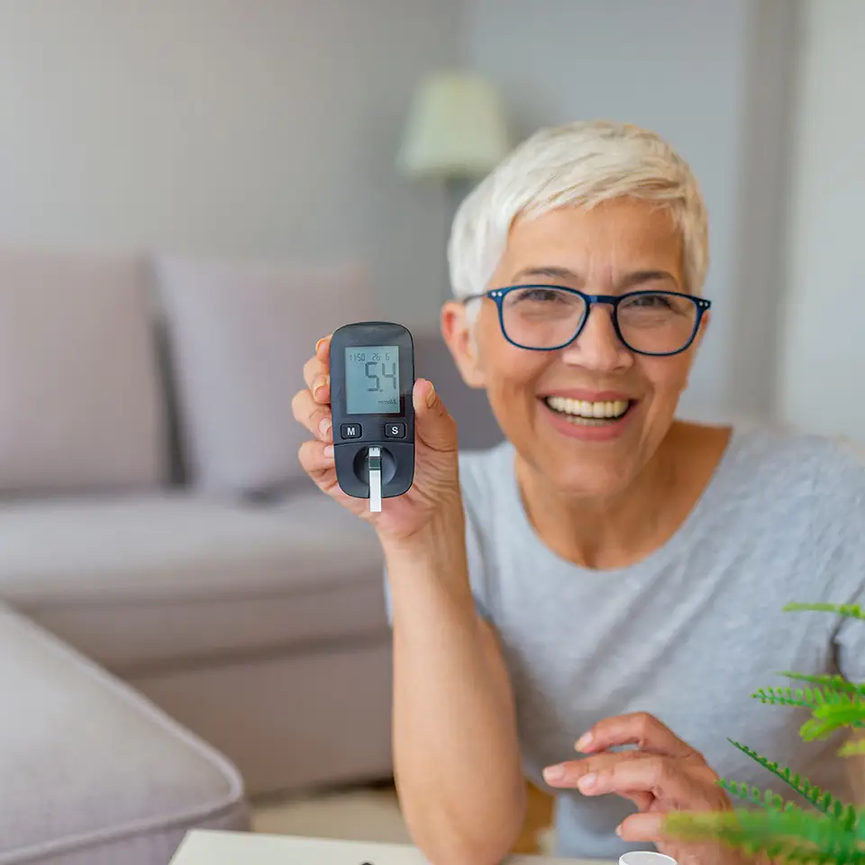 Smiling woman holding up a blood glucose meter