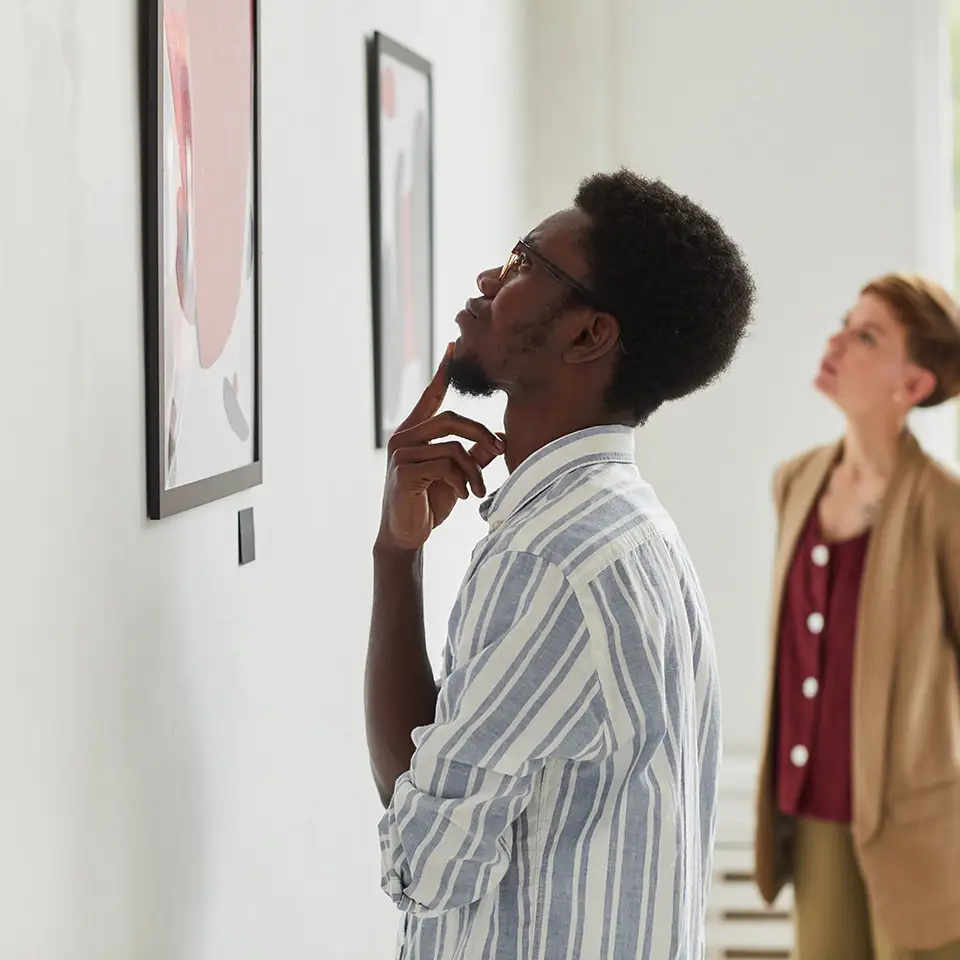 Side view portrait of man looking at paintings while exploring a modern art gallery exhibition