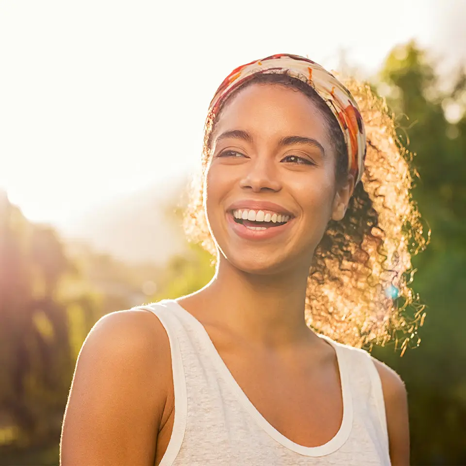 Smiling woman lit by the sun outdoors