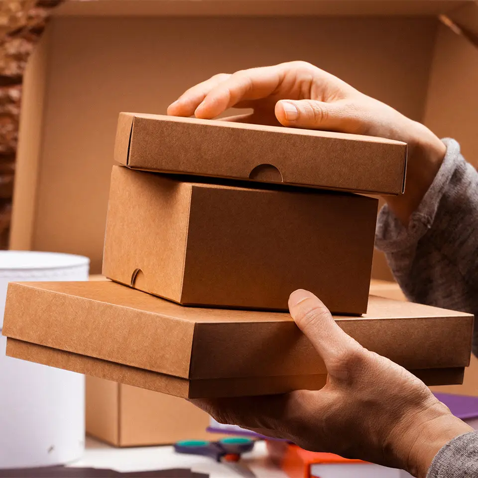 Pair of hands holding a pile of cardboard boxes