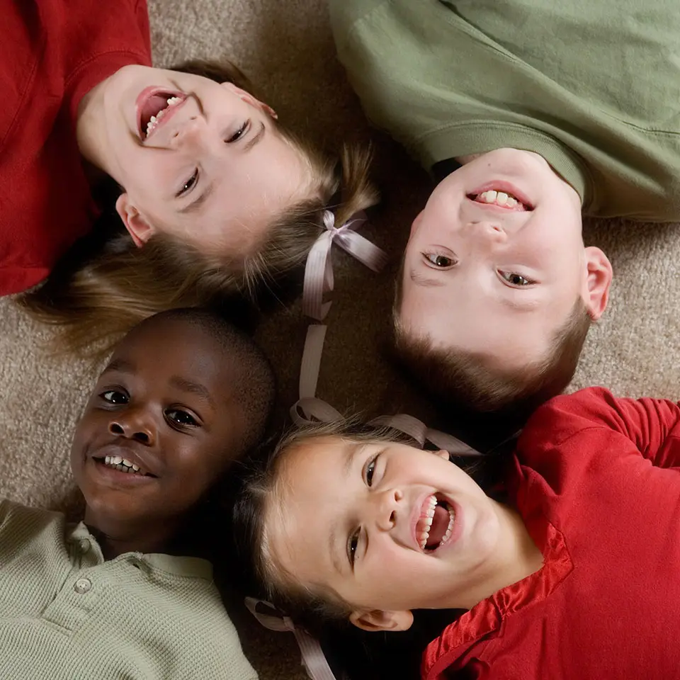 4 happy children lying on the floor