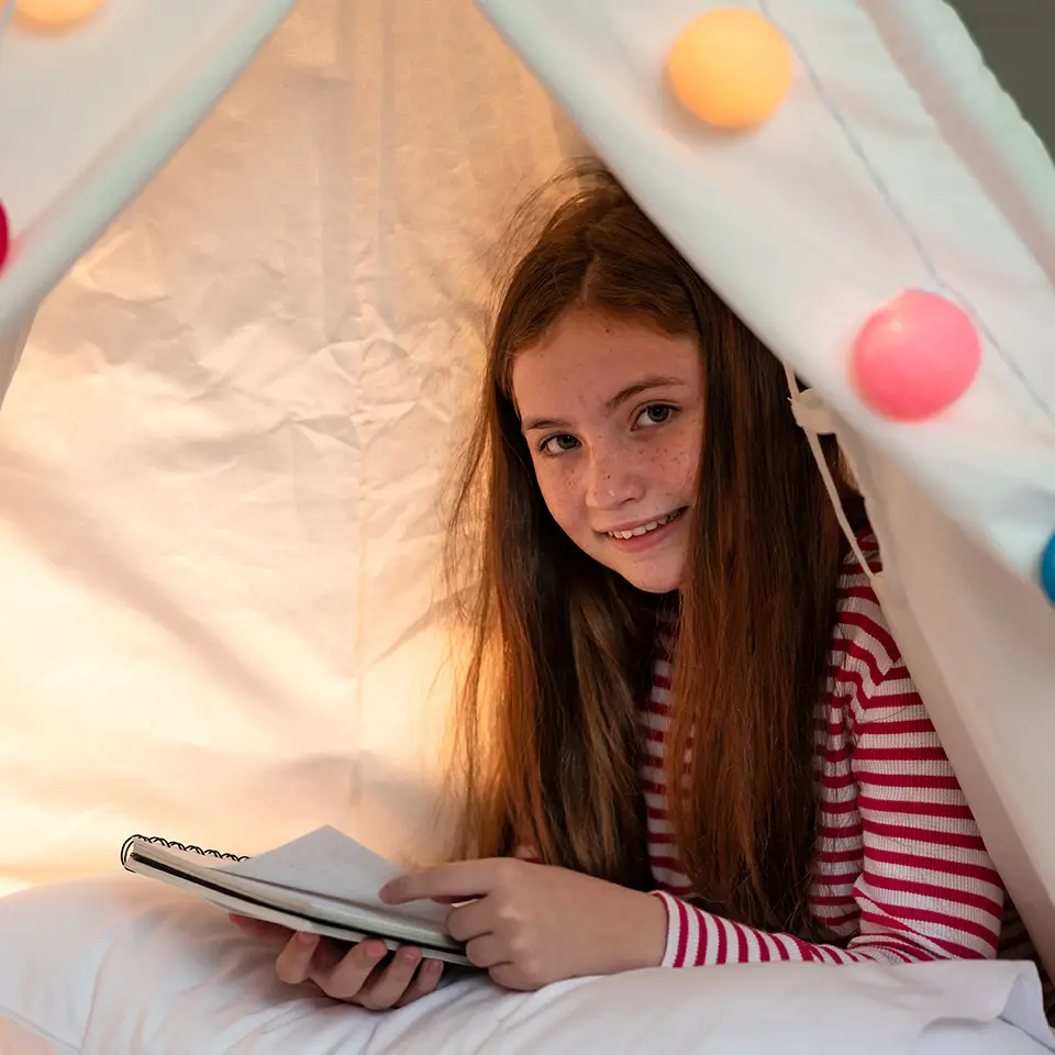Girl writing a story in a teepee