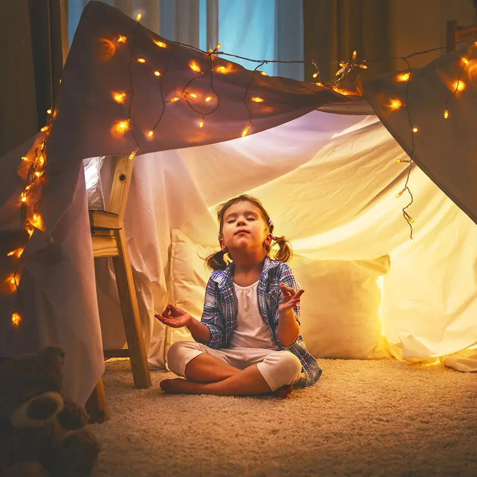 Girl meditating in a tent in her home