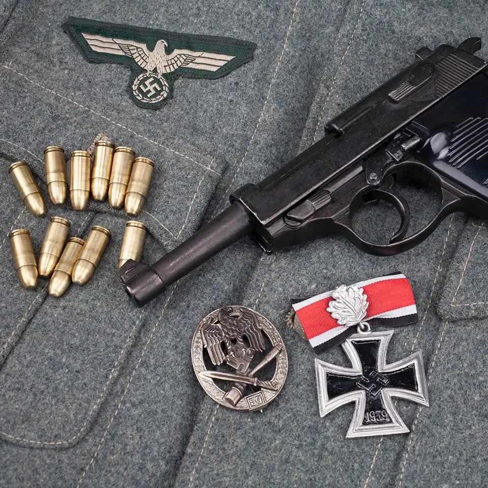 WWII-era Nazi German army 9mm semi-automatic pistol with Iron Cross award on army grey uniform background