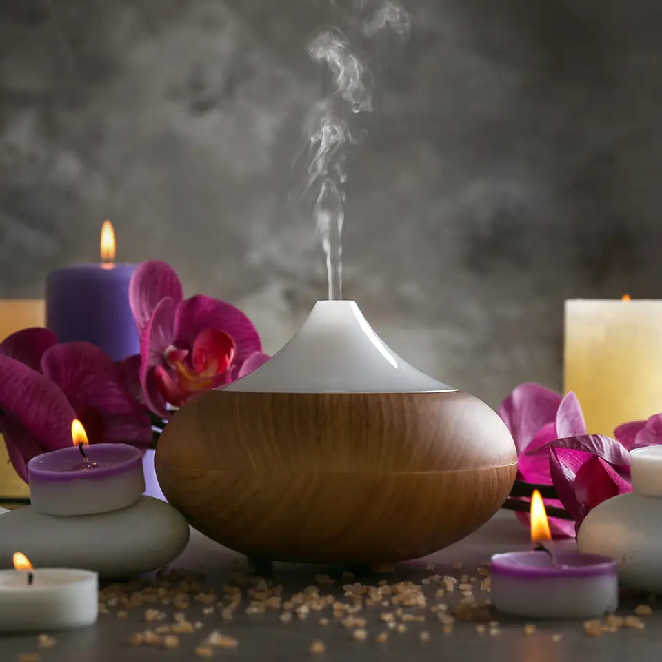 Essential oil diffuser, candles and flowers on a table