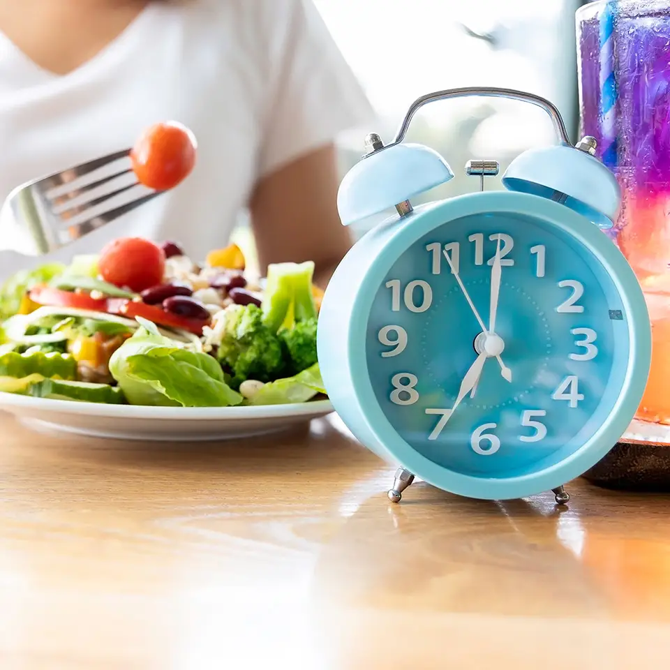 Blue clock and a woman eating a healthy meal