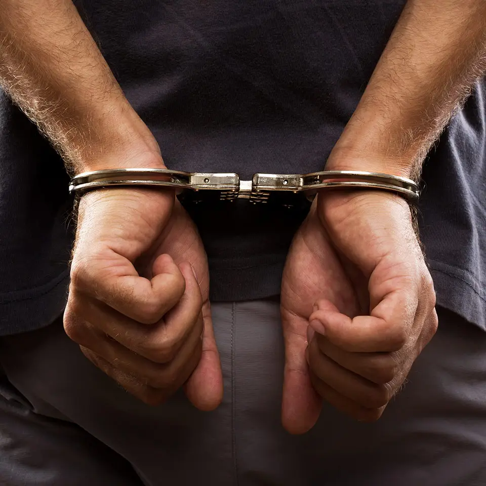 A pair of man's hands handcuffed at his back