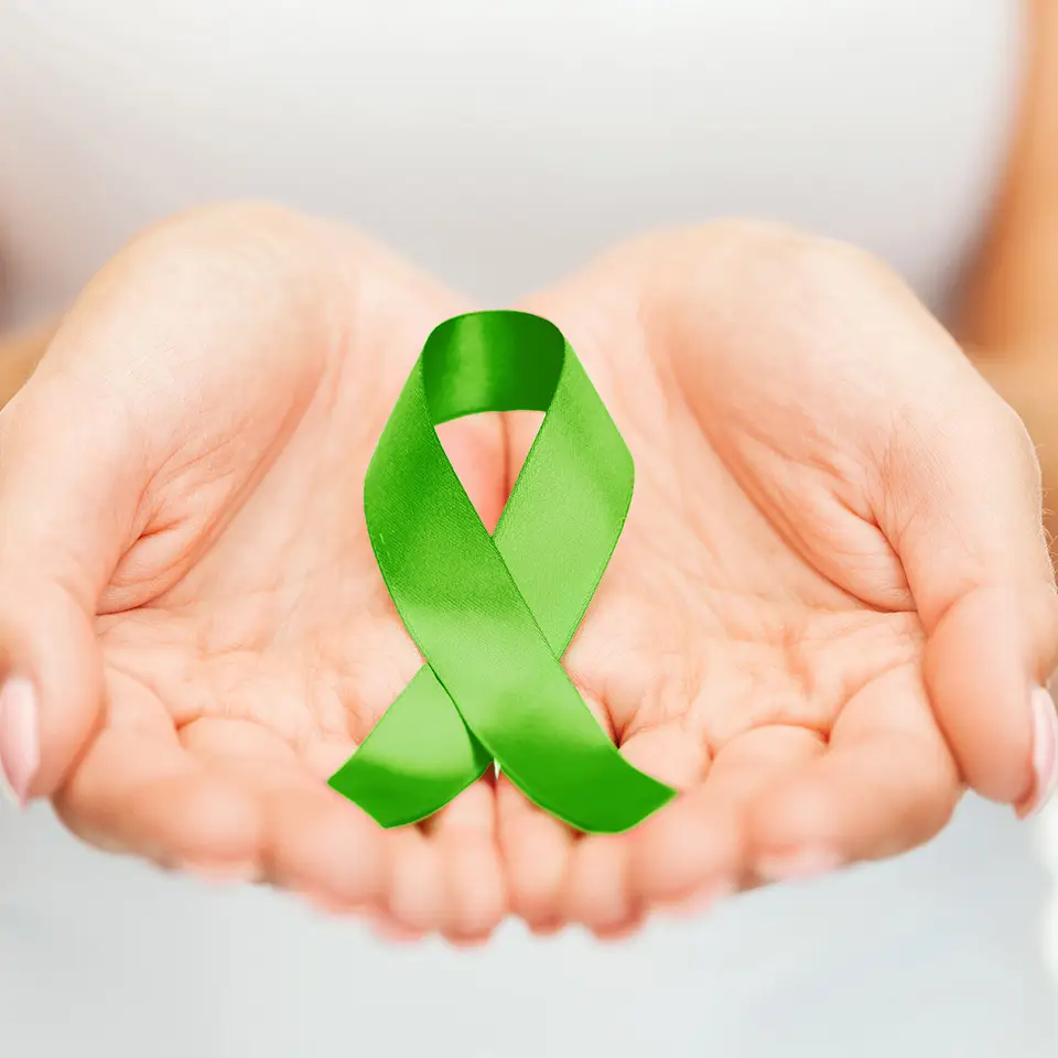 Woman's hands cradling a green ribbon - the symbol of bipolar awareness