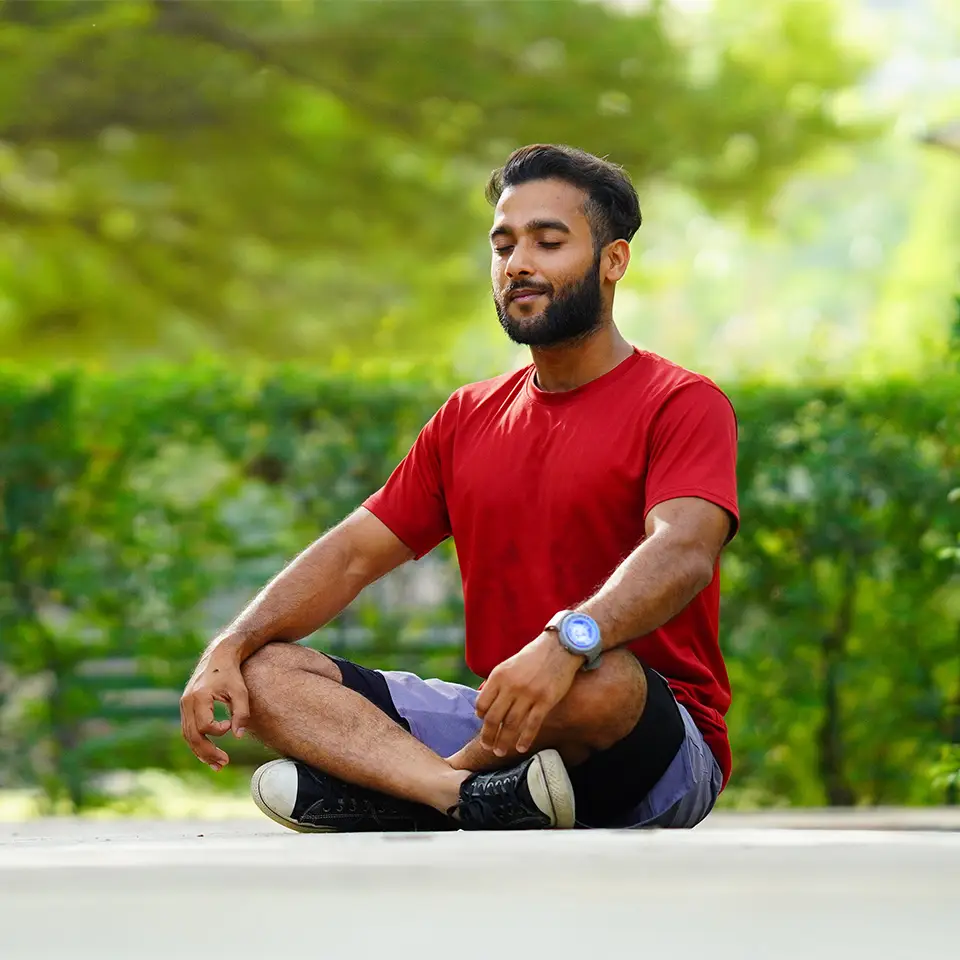 A man sat in a meditation pose outdoors