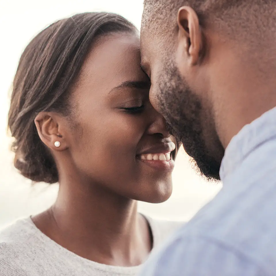 Smiling young couple standing face to face with their eyes closed