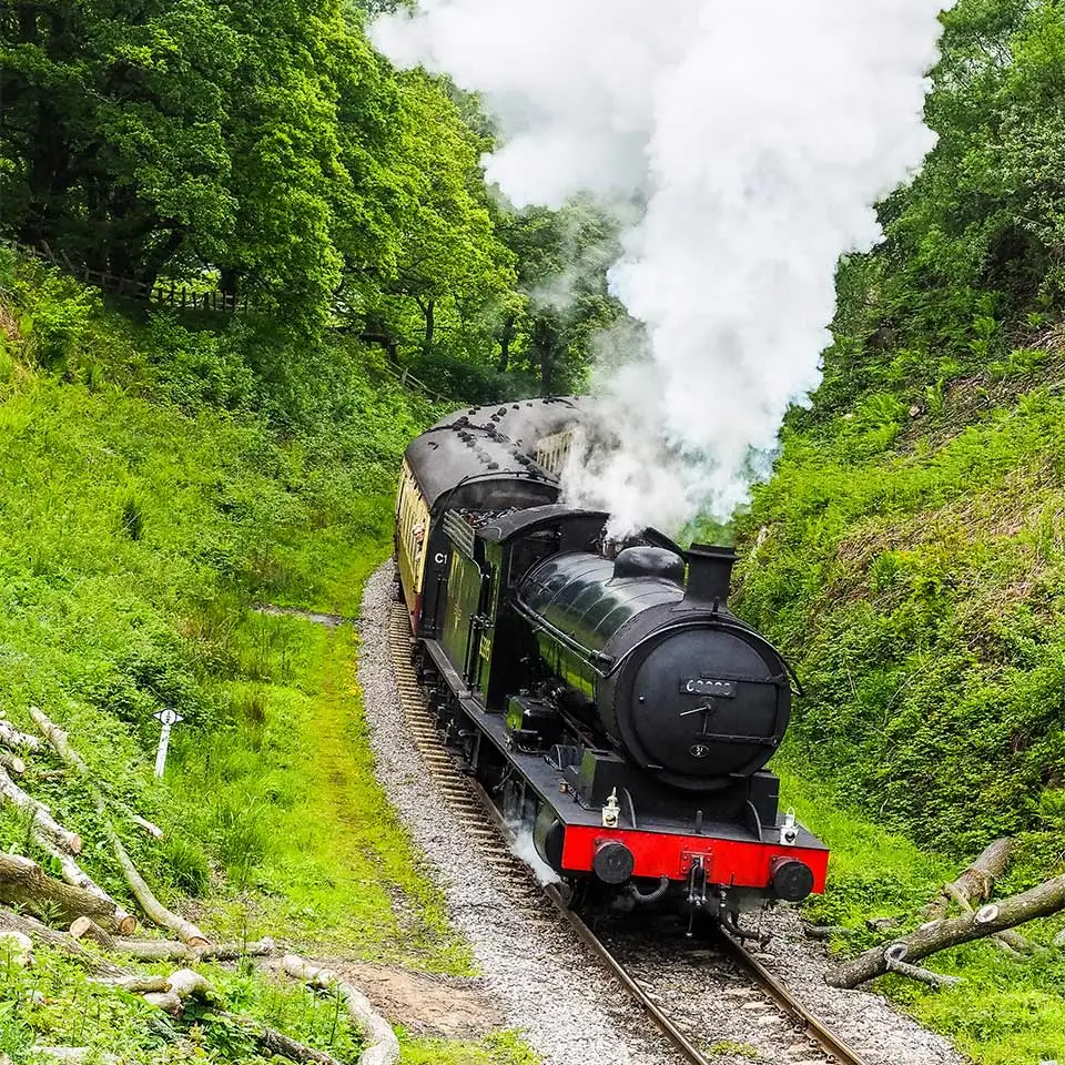 A steam train making its way down a slope in the countryside