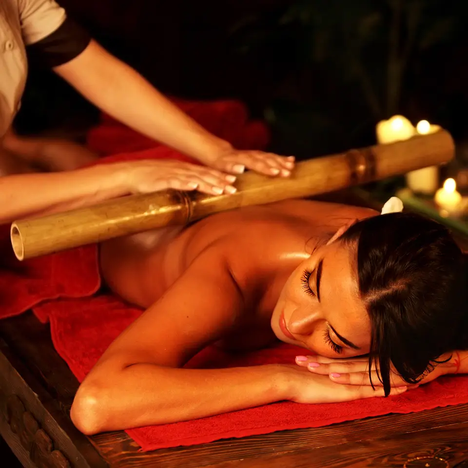 Woman being provided with a warm bamboo massage in a spa setting