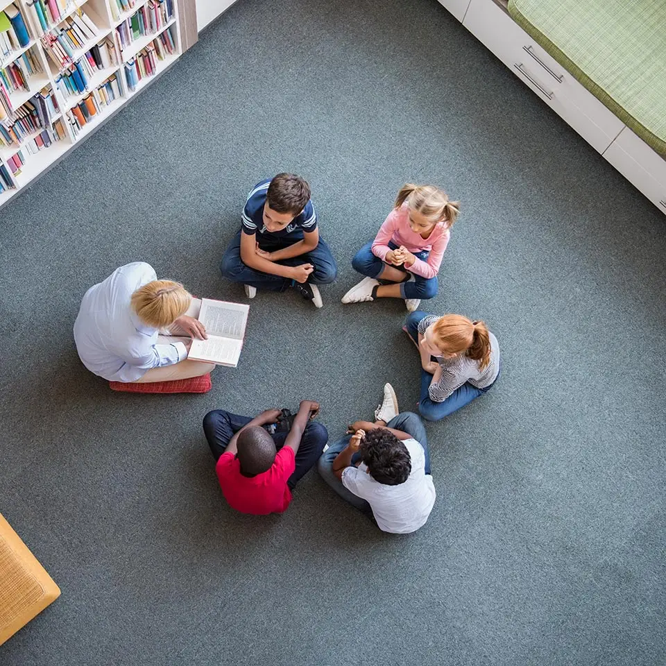 An adult reading a book to children sitting in a circle at a library