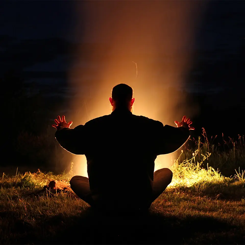 A person sat crosslegged as the meditate in front of an elemental flame