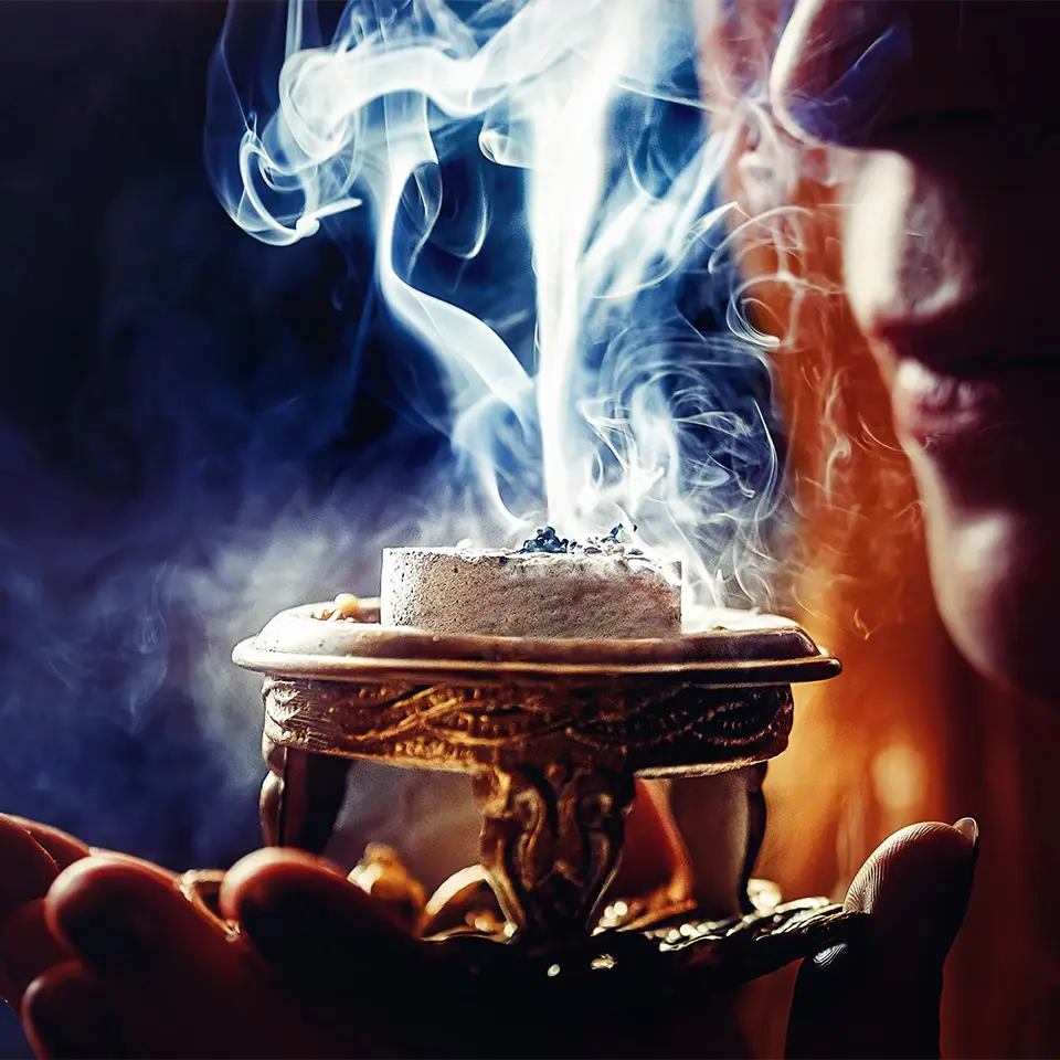 Incense burning in a vase held in a woman’s hand