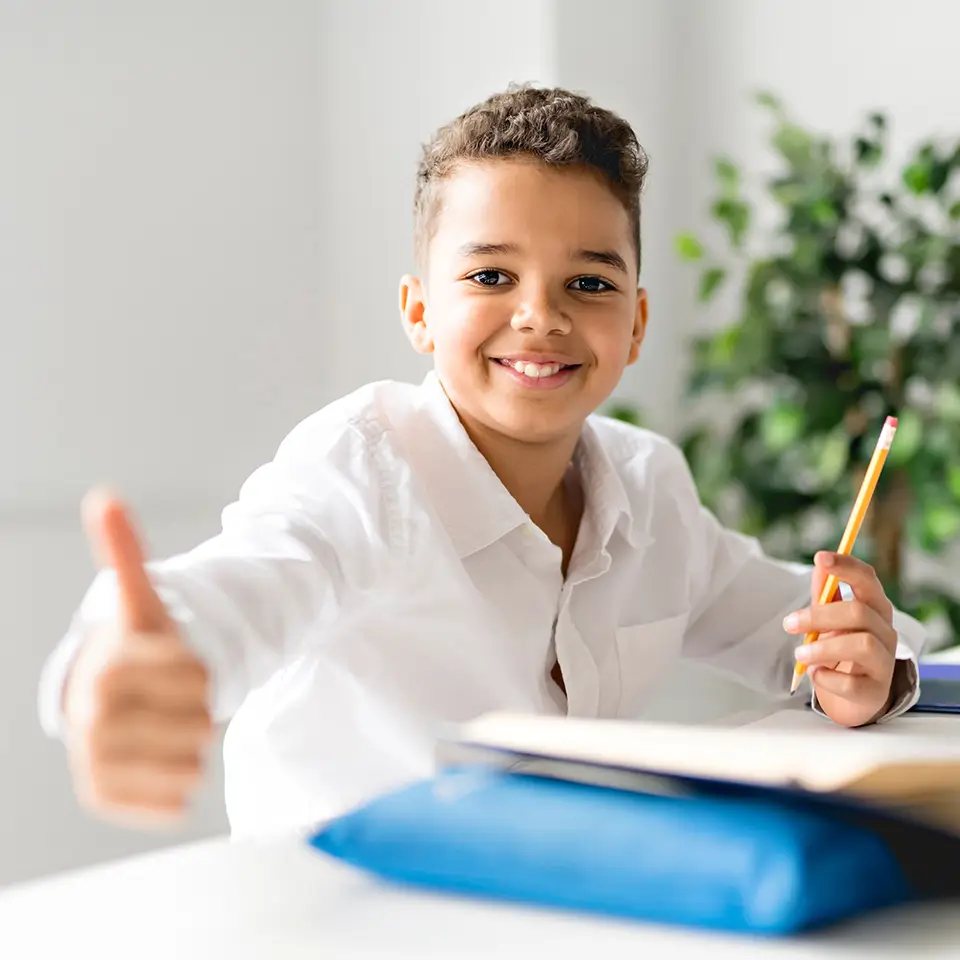 Boy working on English homework and giving a thumbs up